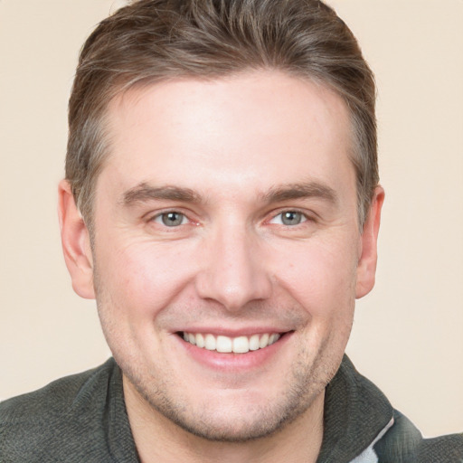 Joyful white young-adult male with short  brown hair and grey eyes