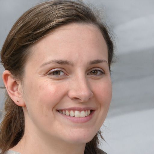 Joyful white young-adult female with medium  brown hair and grey eyes