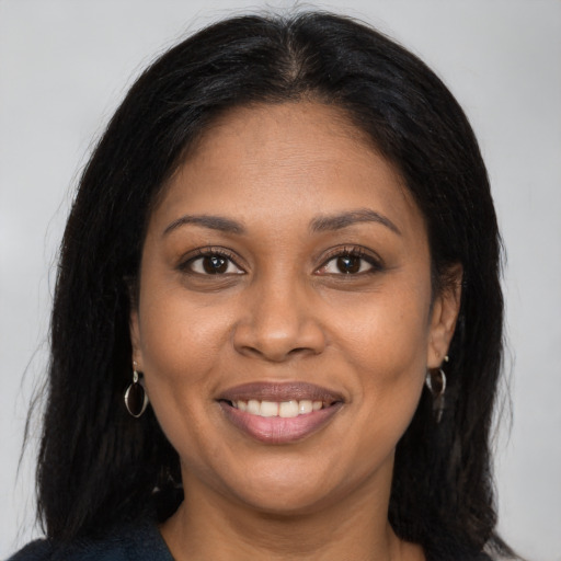 Joyful black adult female with long  brown hair and brown eyes