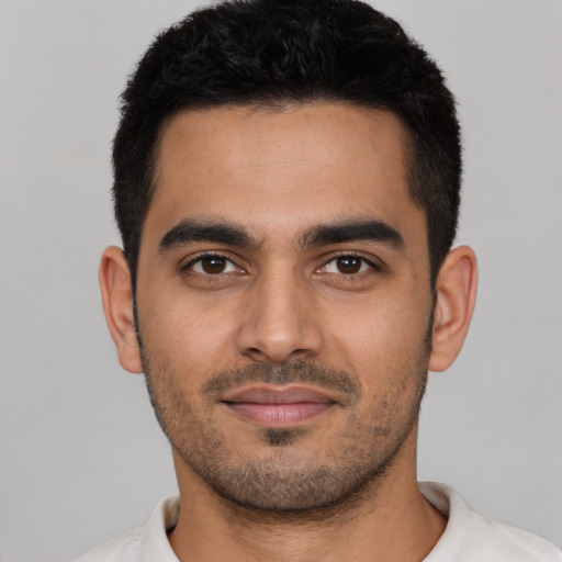 Joyful latino young-adult male with short  black hair and brown eyes