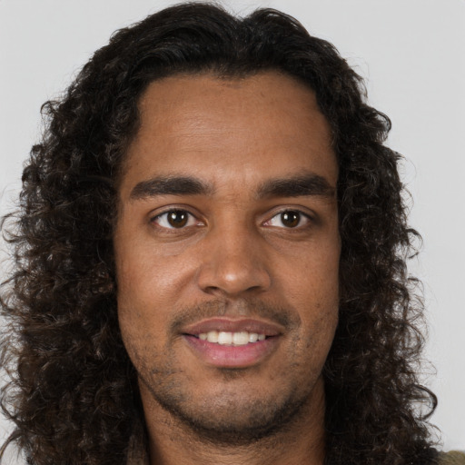 Joyful black young-adult male with long  brown hair and brown eyes