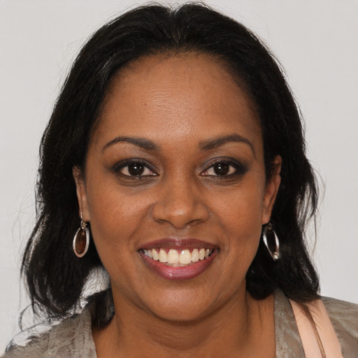 Joyful black young-adult female with long  brown hair and brown eyes