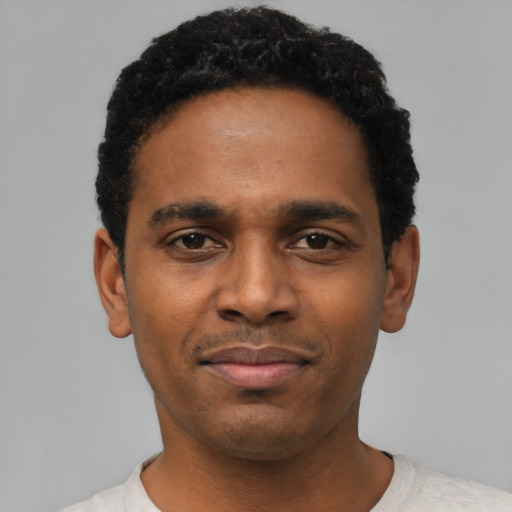 Joyful black young-adult male with short  black hair and brown eyes