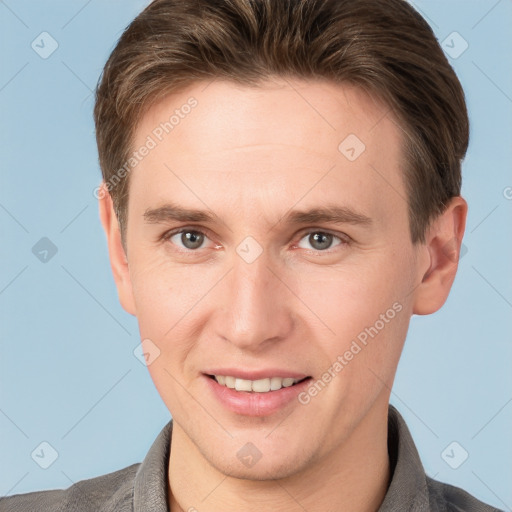 Joyful white young-adult male with short  brown hair and grey eyes