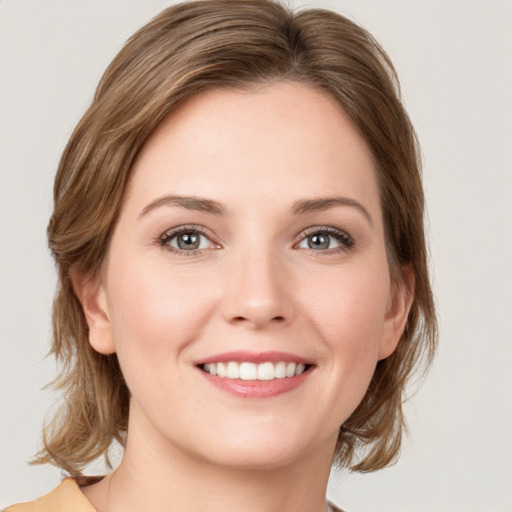 Joyful white young-adult female with medium  brown hair and green eyes