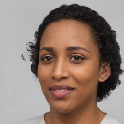Joyful black young-adult female with short  black hair and brown eyes