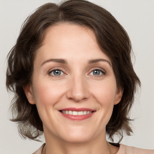 Joyful white adult female with medium  brown hair and grey eyes