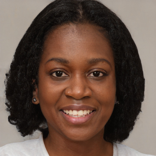 Joyful black young-adult female with medium  brown hair and brown eyes