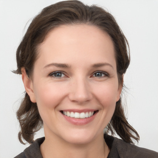 Joyful white young-adult female with medium  brown hair and grey eyes