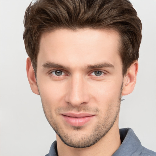 Joyful white young-adult male with short  brown hair and grey eyes