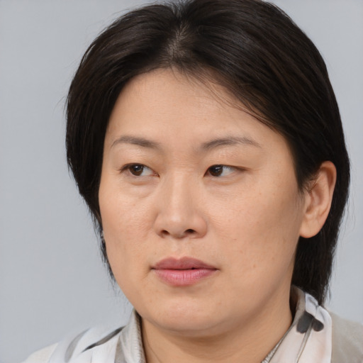 Joyful asian adult female with medium  brown hair and brown eyes