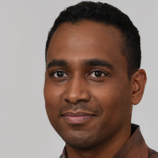 Joyful black young-adult male with short  black hair and brown eyes
