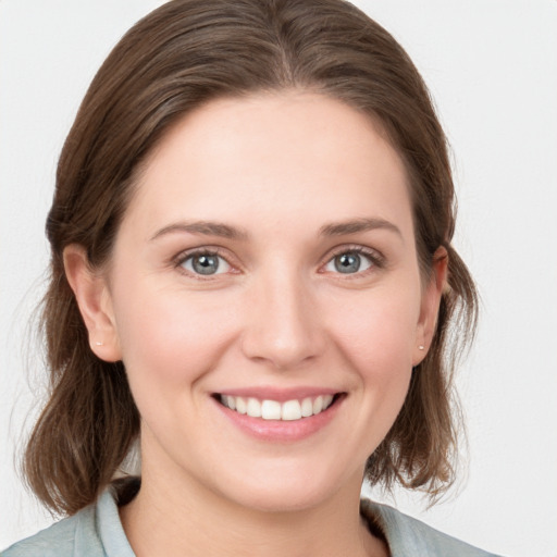 Joyful white young-adult female with medium  brown hair and grey eyes