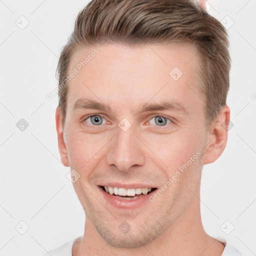 Joyful white young-adult male with short  brown hair and grey eyes