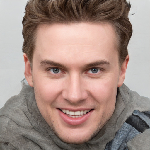 Joyful white young-adult male with short  brown hair and blue eyes