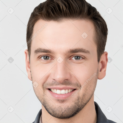 Joyful white young-adult male with short  brown hair and grey eyes