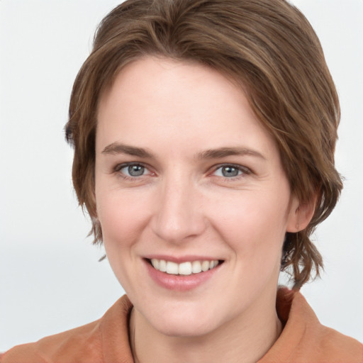 Joyful white young-adult female with medium  brown hair and grey eyes