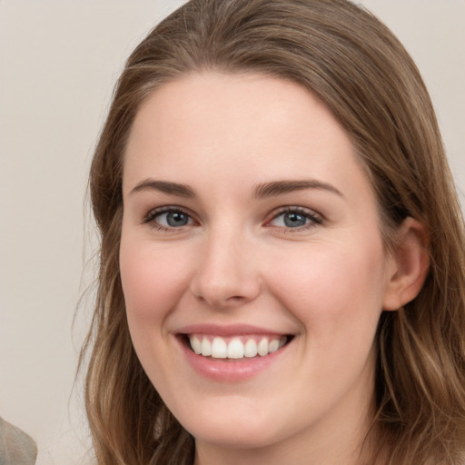 Joyful white young-adult female with long  brown hair and grey eyes