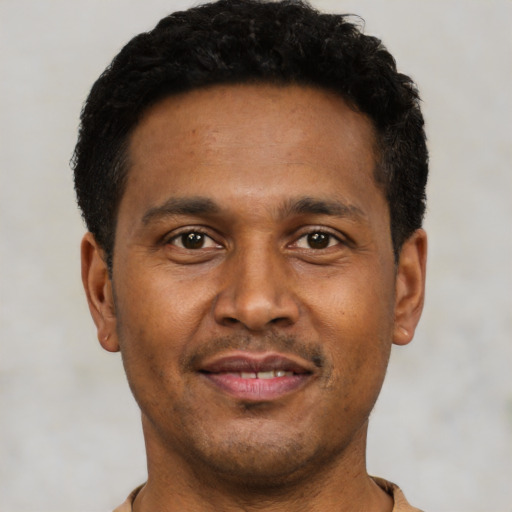 Joyful black young-adult male with short  black hair and brown eyes