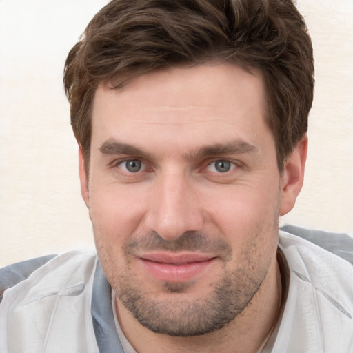 Joyful white young-adult male with short  brown hair and grey eyes