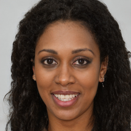 Joyful black young-adult female with long  brown hair and brown eyes
