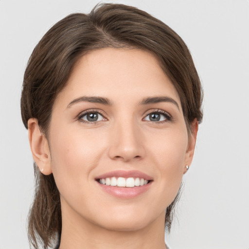 Joyful white young-adult female with medium  brown hair and grey eyes