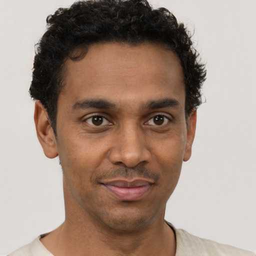 Joyful black young-adult male with short  brown hair and brown eyes