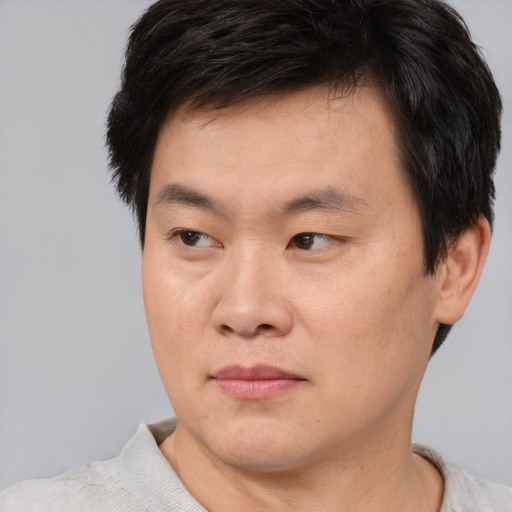 Joyful asian young-adult male with short  brown hair and brown eyes