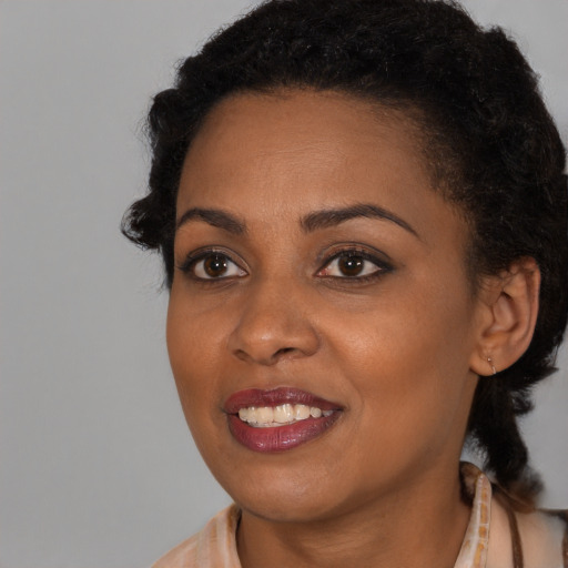 Joyful black young-adult female with long  brown hair and brown eyes