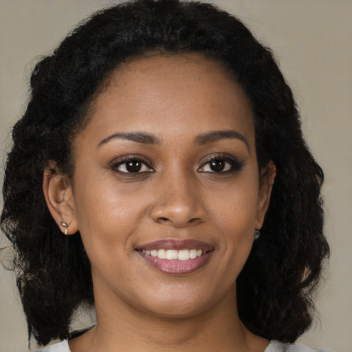 Joyful black young-adult female with long  brown hair and brown eyes