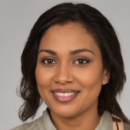 Joyful black young-adult female with long  brown hair and brown eyes