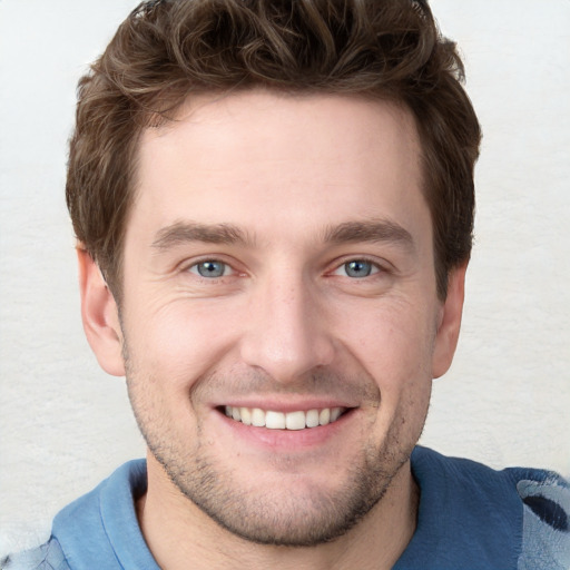 Joyful white young-adult male with short  brown hair and blue eyes