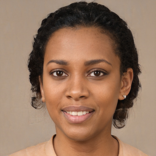 Joyful black young-adult female with long  black hair and brown eyes