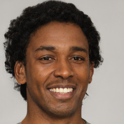 Joyful black young-adult male with short  brown hair and brown eyes