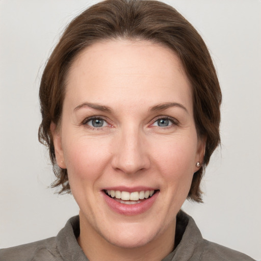 Joyful white adult female with medium  brown hair and grey eyes