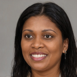 Joyful black young-adult female with long  brown hair and brown eyes