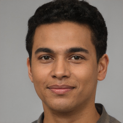 Joyful latino young-adult male with short  black hair and brown eyes