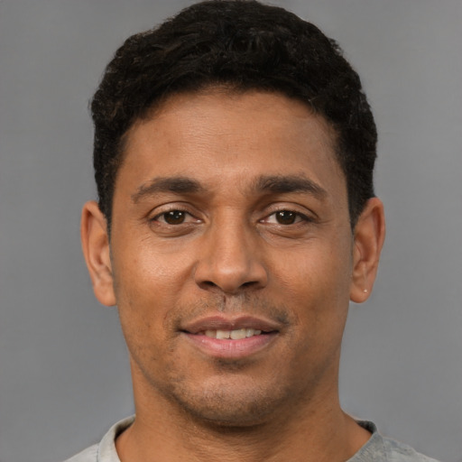 Joyful latino young-adult male with short  brown hair and brown eyes