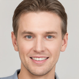 Joyful white young-adult male with short  brown hair and grey eyes