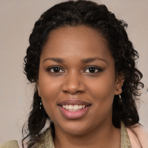 Joyful black young-adult female with long  black hair and brown eyes