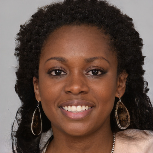 Joyful black young-adult female with long  brown hair and brown eyes