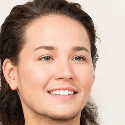 Joyful white young-adult male with long  brown hair and brown eyes