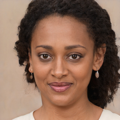 Joyful black young-adult female with long  brown hair and brown eyes