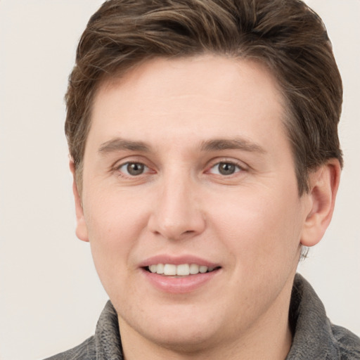 Joyful white young-adult male with short  brown hair and grey eyes