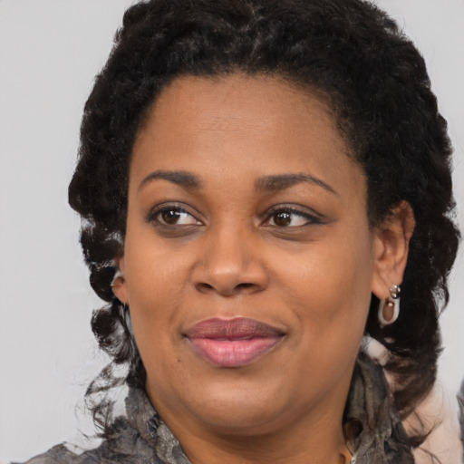 Joyful black adult female with long  brown hair and brown eyes