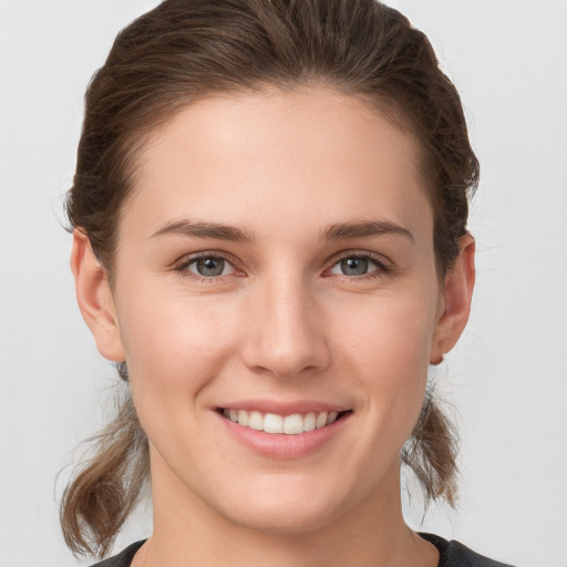 Joyful white young-adult female with medium  brown hair and grey eyes