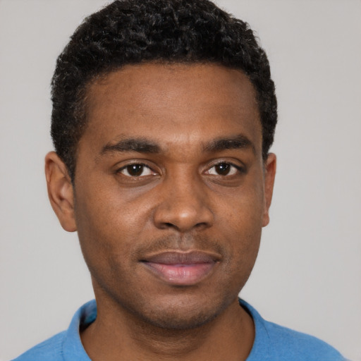 Joyful black young-adult male with short  black hair and brown eyes