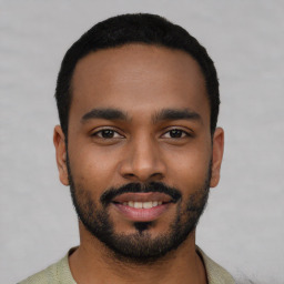 Joyful black young-adult male with short  black hair and brown eyes