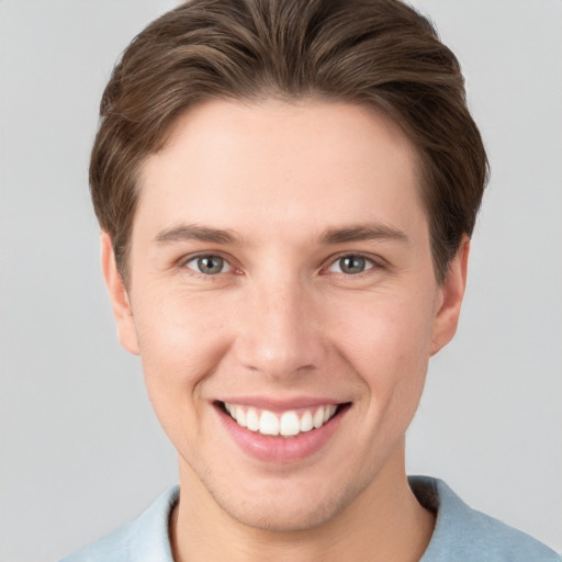 Joyful white young-adult male with short  brown hair and grey eyes