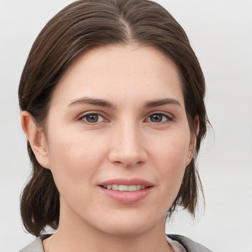 Joyful white young-adult female with medium  brown hair and grey eyes